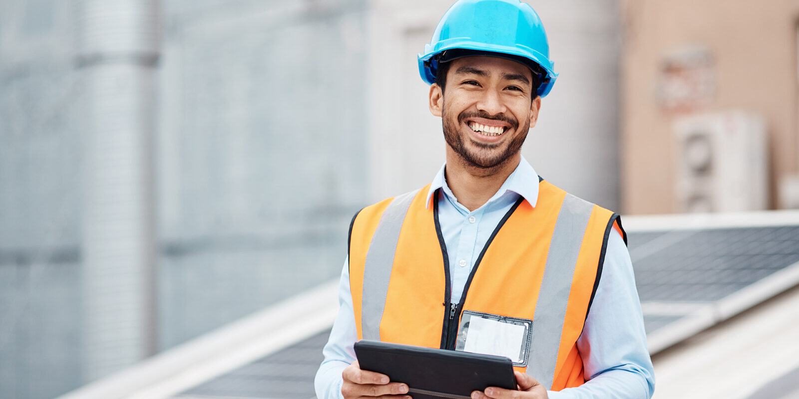 Energy-1 MBS Energy student at job site wearing hard hat and holding tablet